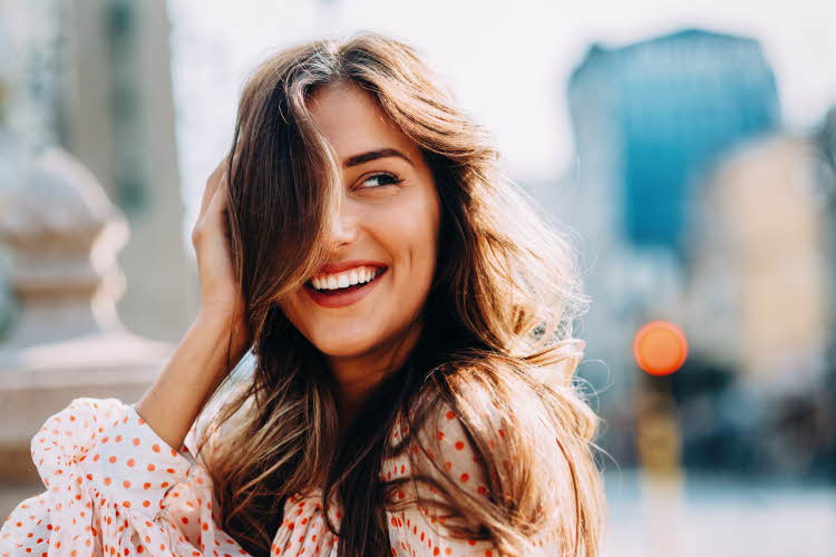 Smilende kvinne med bølgete langt hår som blåser
