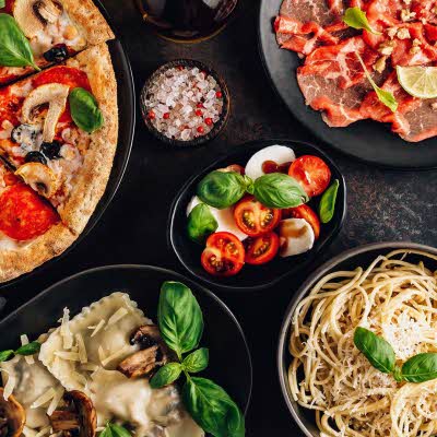 et bord med diverse italienske pasta retter, pizza og annet