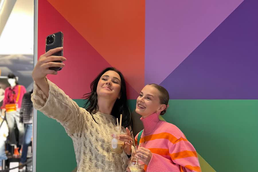 To jenter tar selfie foran fargevegg