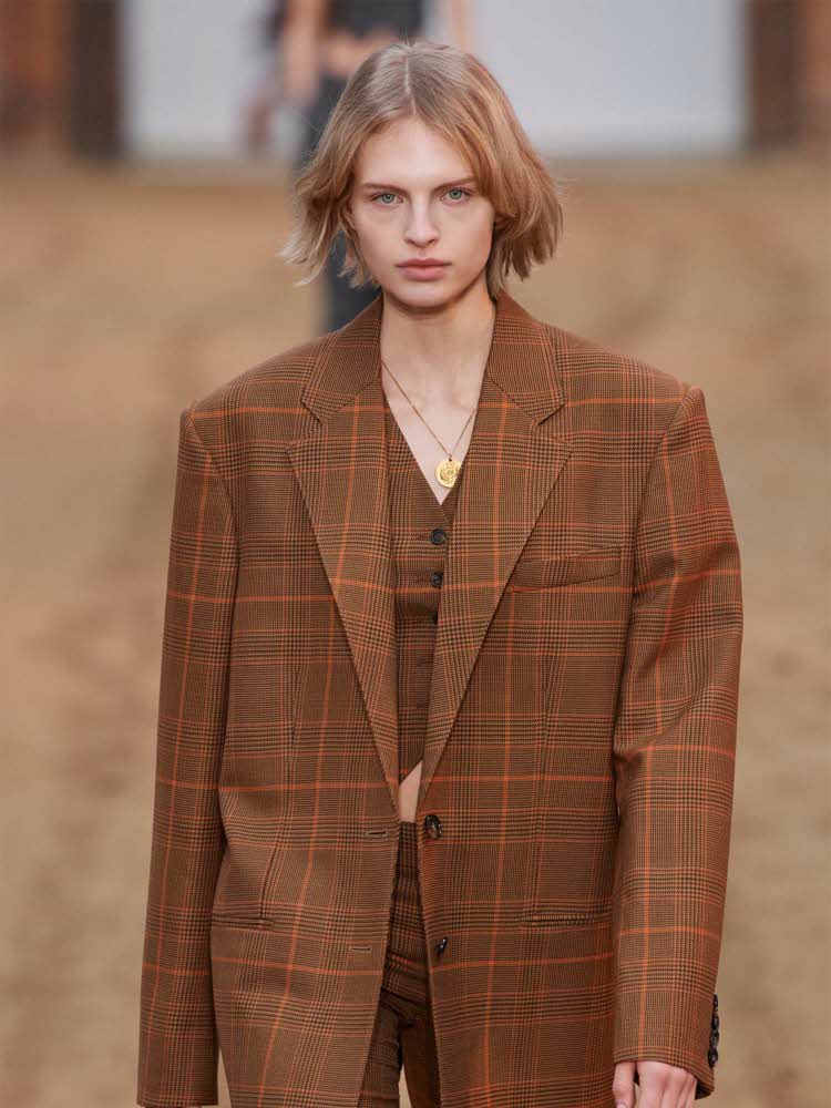 Damemodell på catwalk med rutete dressjakke, bukse og vest.