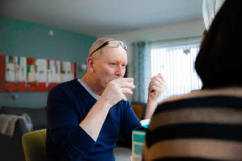 Mann som sitter og drikker kaffe sammen med en dame ved kjøkkenbordet