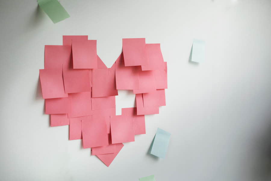 Hvit vegg med rosa post-it-lapper som utgjør en hjerteform