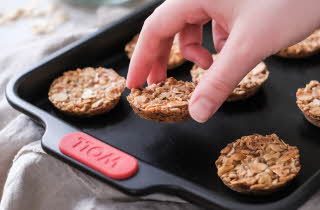 En hånd som plukker opp en kjeks fra et stekebrett.