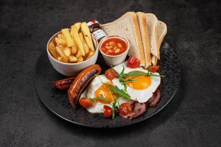 tallerken med egg, tomater, toast, bønner, pommes frites, pølse og syltetøy