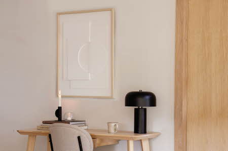 Et minimalistisk bilde hengende på en hvit vegg og over et skrivebord av tre