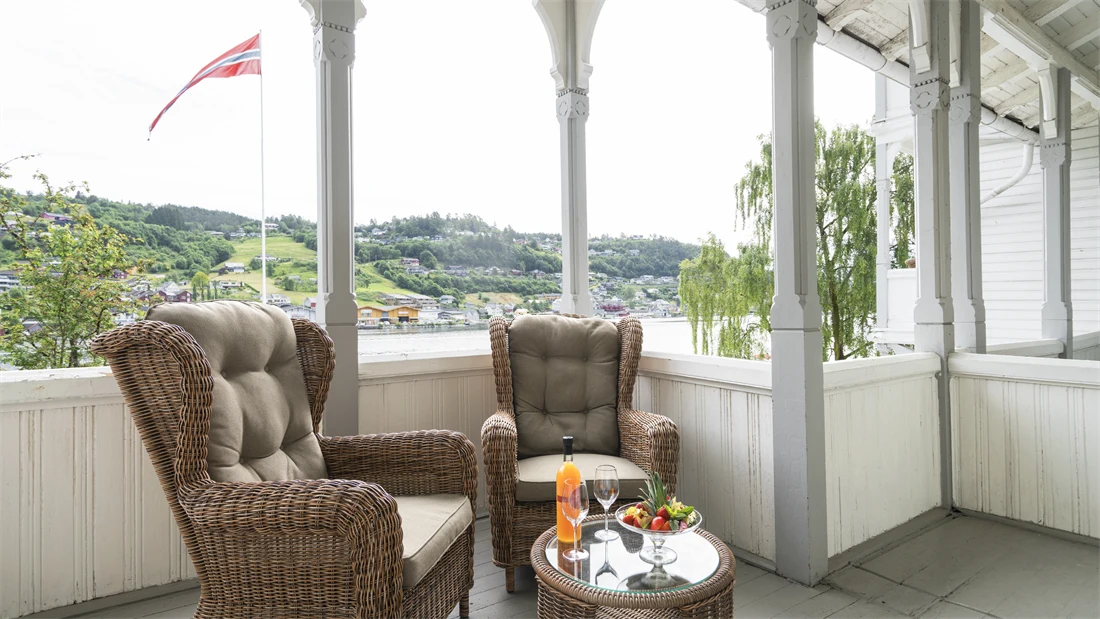 Veranda med peoner på bordet, eplemost i flaske og verandastoler på Thon Hotel Sandven i Nordheimsund