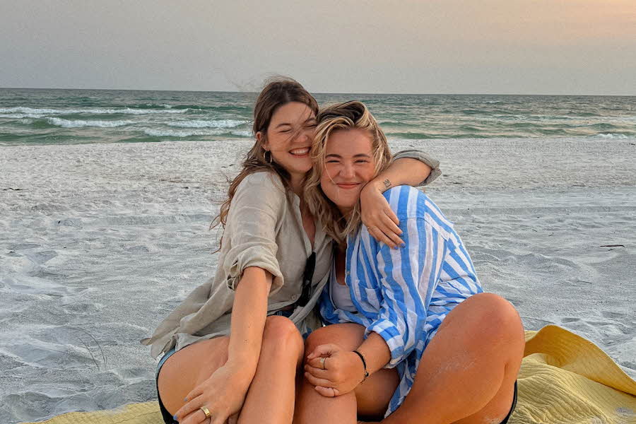 To damer som klemmer hverandre og sitter på en strand