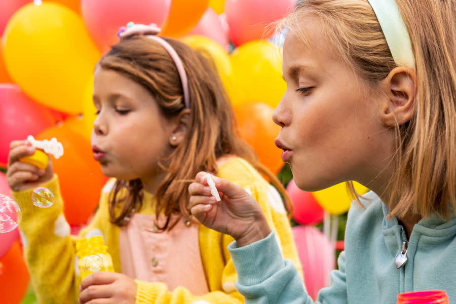 barn blåser såpebobler, fargerike ballonger i bakgrunn