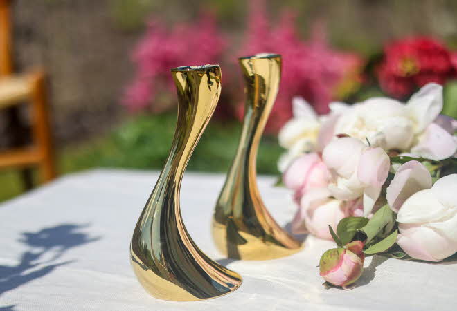 To Cobra lysestaker fra Georg Jensen som står på et bord ute med en bukett ved siden av