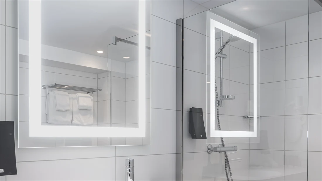 Vask, speil med led lys rundt og dusj på bad i business rom på Thon Hotel Bristol Bergen.