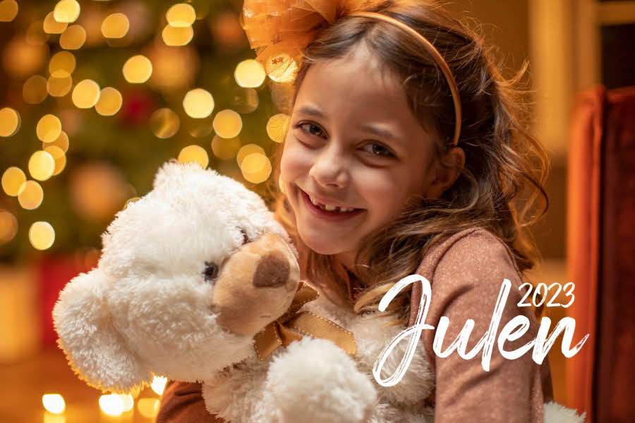 Jente som smiler til kamera og holder en hvit bamse