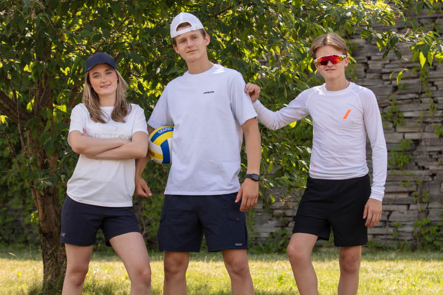 Tre ungdom som poserer for kamera i gymtøy og med volleyball