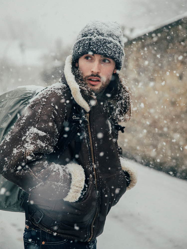 Mann i semsket jakke går i snøvær 