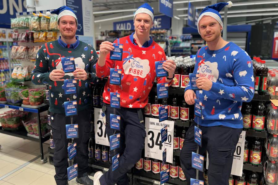 Tre Rema-ansatte med julegenser og blå nisselue står oppstilt med 24 gavekort i hendene