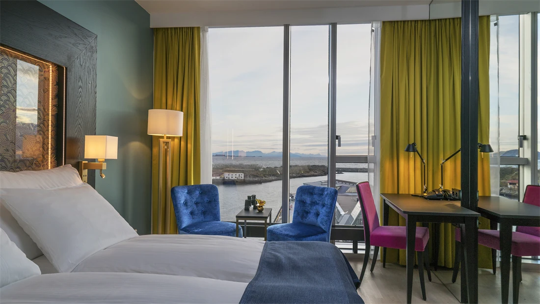 to stoler, dobbeltseng og skrivepult med utsikt på Superior room på Thon hotel Lofoten i Svolvær