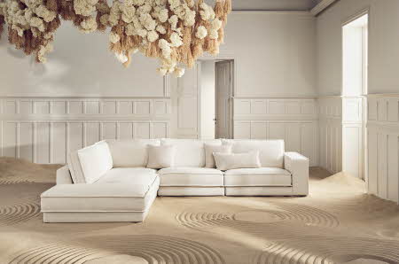 lys stue med sand, hvit modulsofa og blomstrer i taket