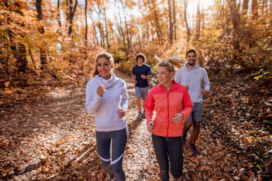 Gjeng med menn og kvinner som løper i skogen om høsten