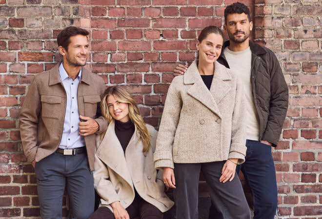 Personer i høstantrekk og lener seg på en murvegg