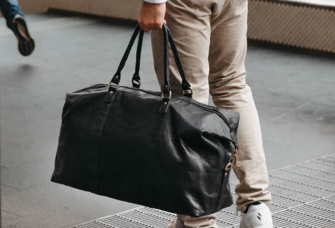 Person med stor svart skinnbag i et innendørs miljø.