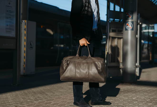 En mann som bærer på en brun bag