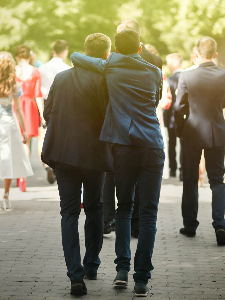 To dresskledde gutter sett bakfra, holder rundt hverandre mens de følger etter andre