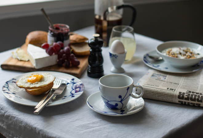 En fjøl med rundstykker, tilbehør og en tallerken med rundstykke og egg.