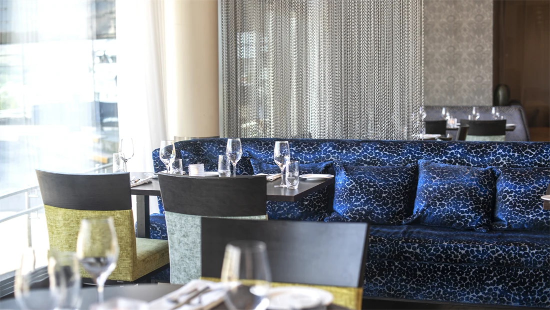 Restaurant, runde spisebord, stoler, blå sofa, vindu