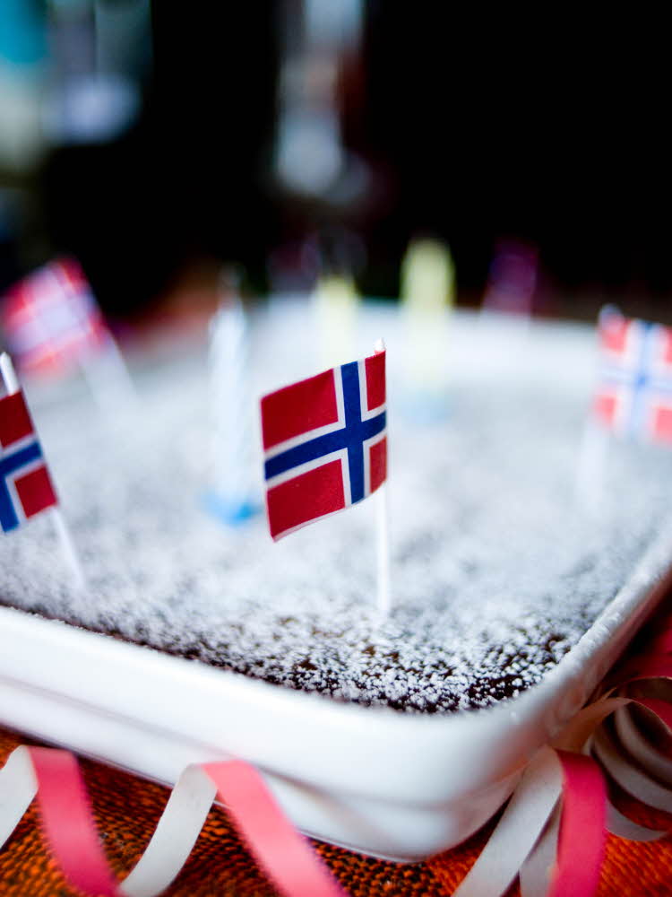 Sjokoladekake pyntet med norgesflagg til 17. mai Vimpler av norgesflagget henger over frokostbordet