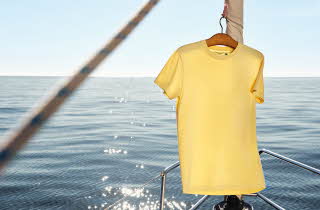 En gul t-skjorte som henger fra en mast fra en båt