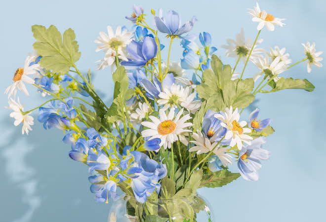 Bukett med hvite og blå blomster i en glassvase.