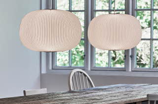 Spisestue med to hvite pendellamper over et rustikt trebord.