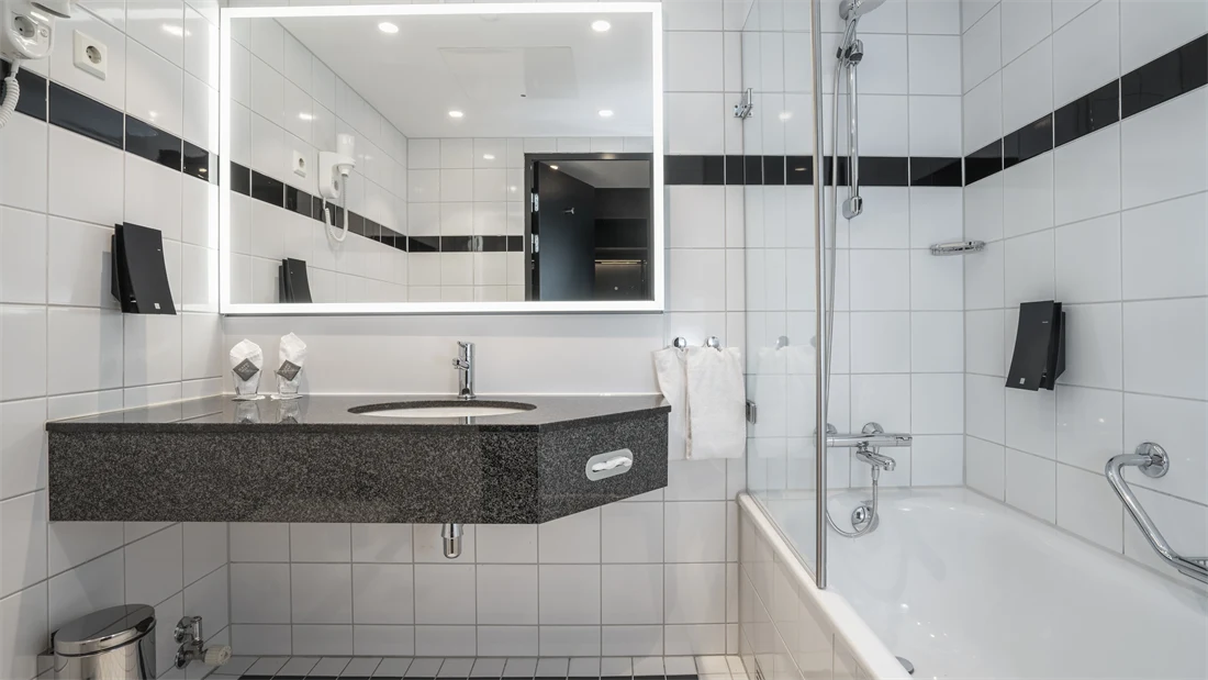 Hvite gulv og veggfliser, badekar med dusj, speil, vask
