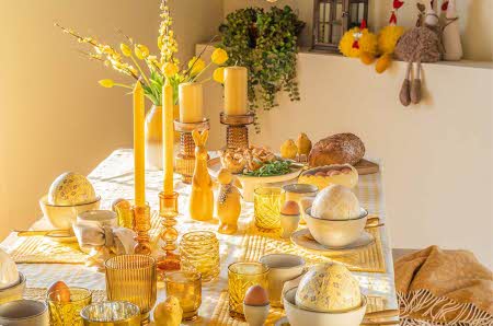 dekket bord med påskepynt, serviser, lysestaker og blomstrer