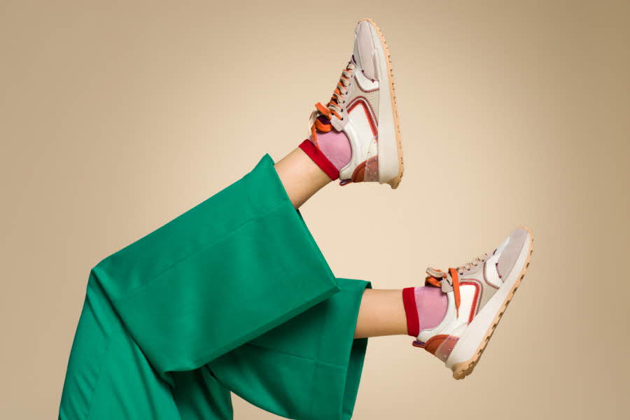 to føtter stikker opp, grønn bukse, rosa og røde sokker, hvite, røde og beige sneakers