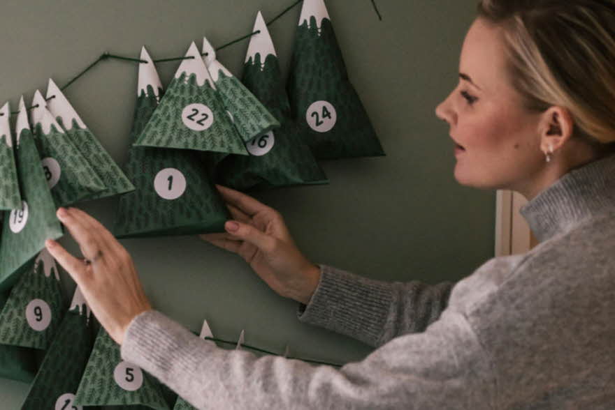 Dame henger opp julekalender på veggen