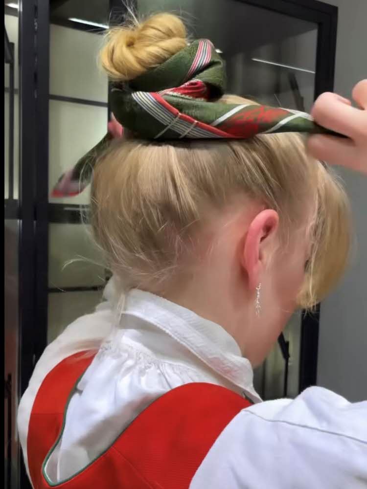 En jente fester bunadsskjerfet i håret