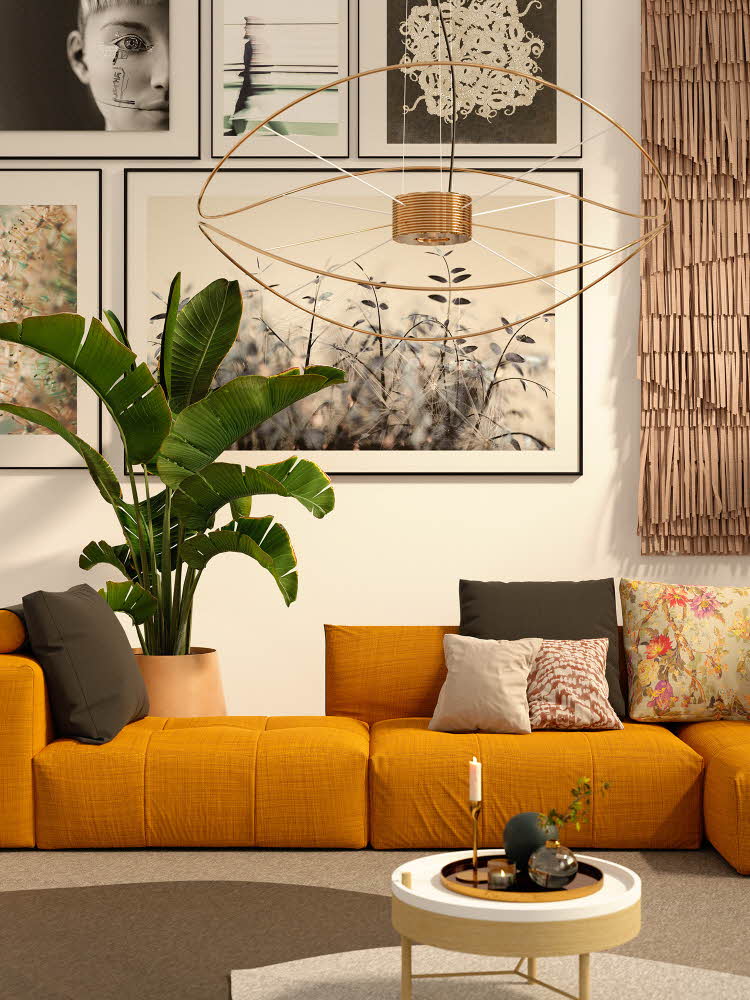 Interiørbilde fra stue med store malerier på veggen og en lav, oransje sofa i sentrum.