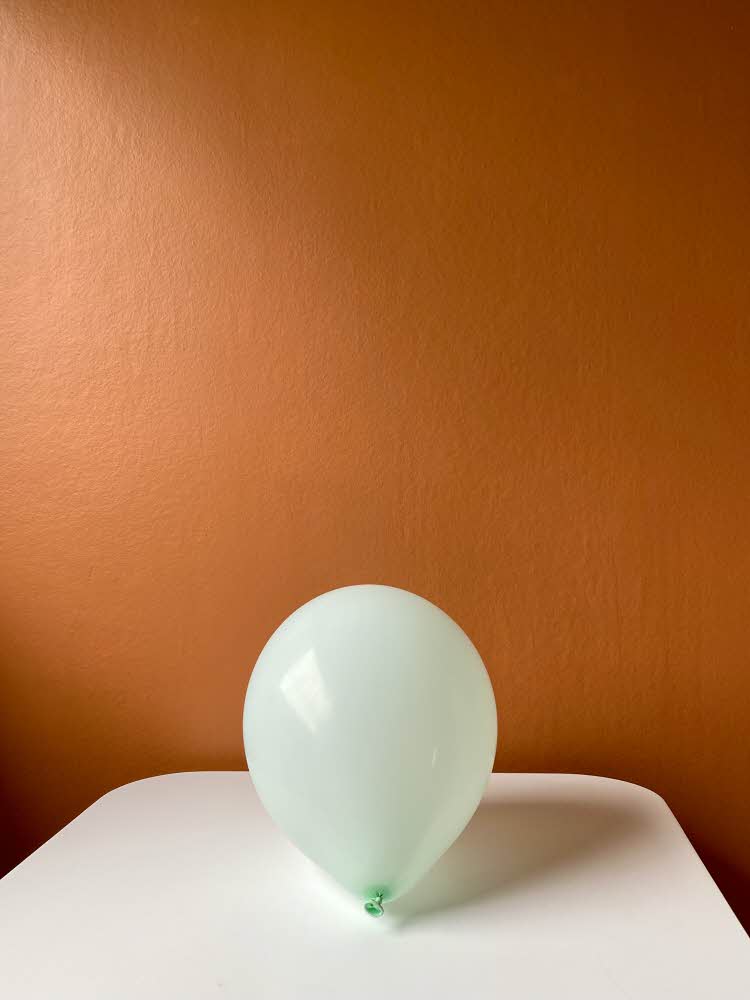 Oppblåst ballong som ligger på et bord med oransje bakgrunn