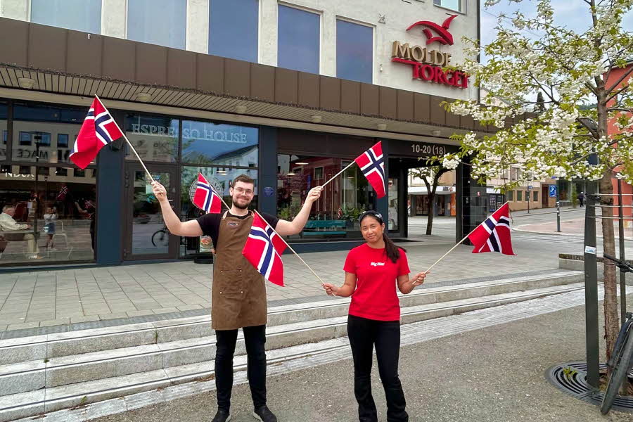 Mann og dame som vifter med flagg utenfor et kjøpesenter