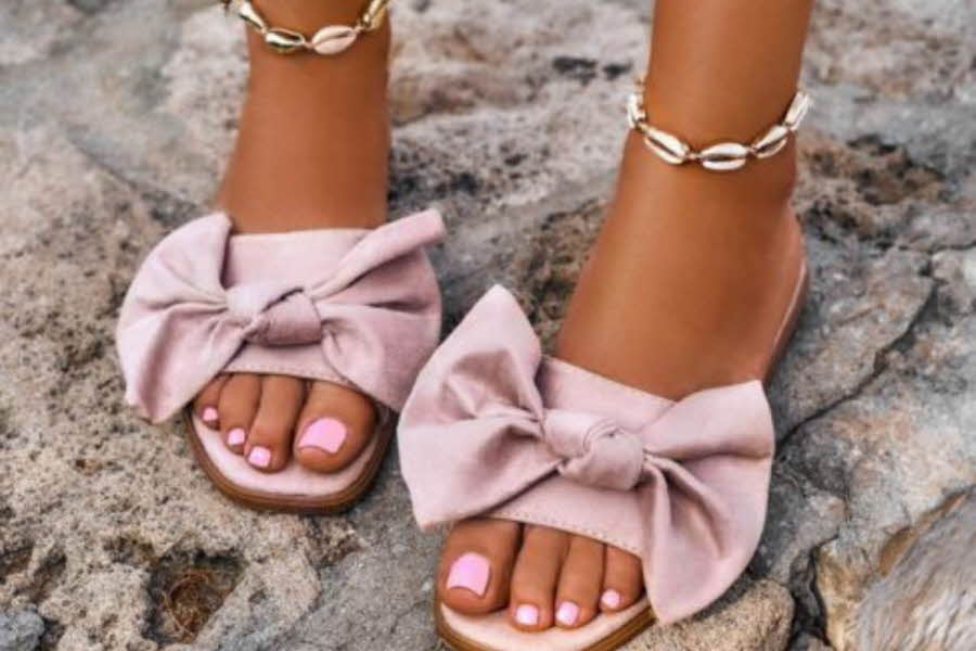 Føtter med lakkerte negler og rosa sandaler med sløyfe