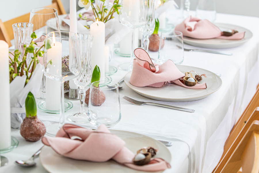 Langbord dekker til gjester med rosa servietter og grønn naturlig dekorasjon