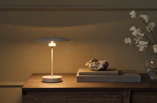 Minimalistisk bordlampe på en trekommode med dekorative detaljer.