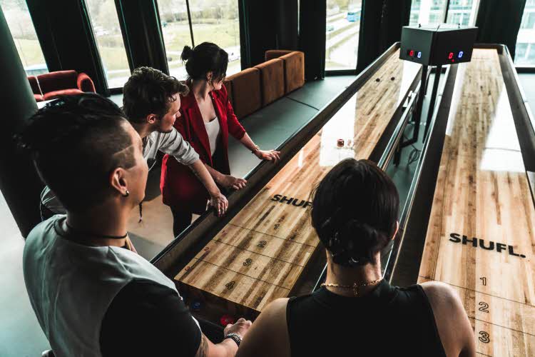4 venner som spiller shuffleboard