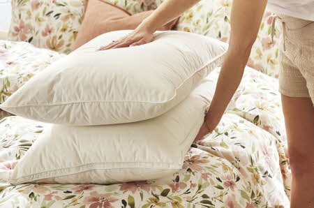 En kvinne som legger to dunputer på en seng