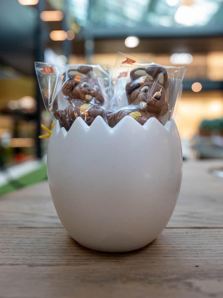 Et halvt kjeramik egg med sjokolade kaniner på pinne 