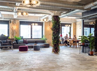 Interiør fra kontoret til The Oslo Company, stor og åpen sosial sone med rustikke detaljer som betonggulv og ventilasjon, grønne planter og lyse farger på veggene