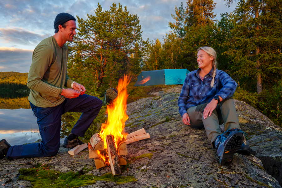 Mann og dame som tenner bål ved ett vann