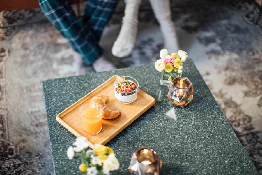 Marmorbord med trefat med en croissant, appelsinjuice og blomster