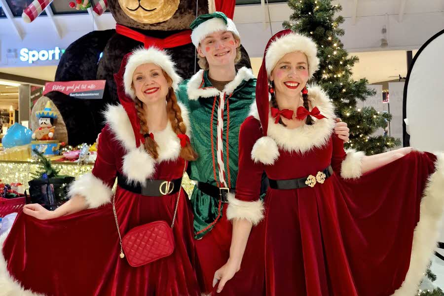 Tre jenter utkledd som nisser og en alv står foran julebamsen på Sørlandssenteret