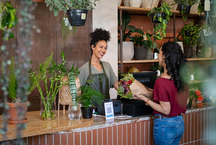 ansatt i blomsterbutikk betjener kunde